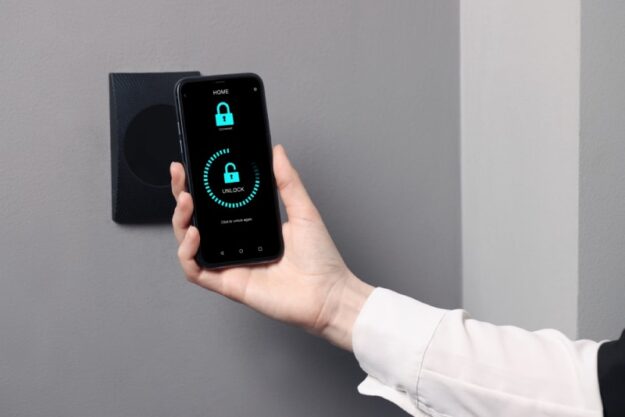 Access Control Solutions for Multi-Tenant Apartments Close-up of a woman's arm as she uses her mobile phone to activate the access control keeping her apartment locked and safe.