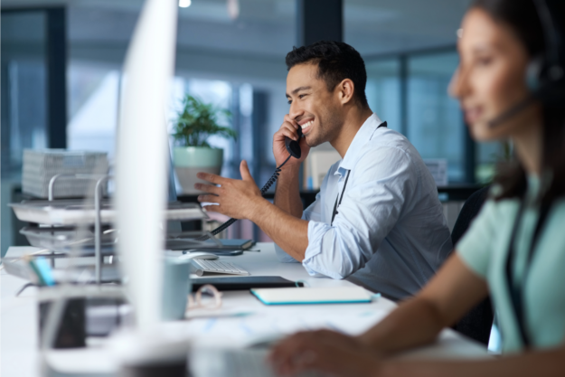 Shot of a young man answering the phone while working in a modern call center.