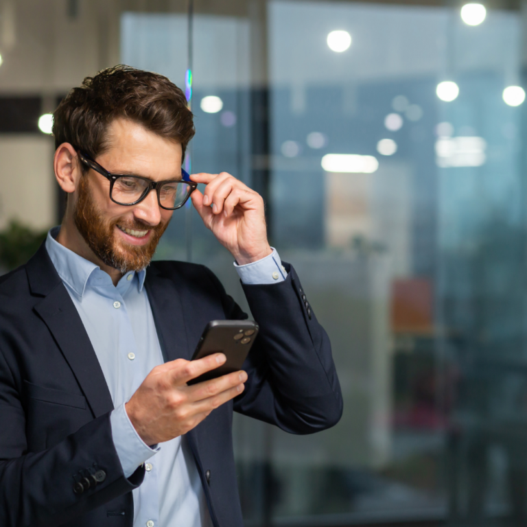 Businessman in business suit uses telephone near window.